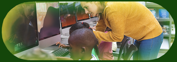 Students working at computers with a teacher